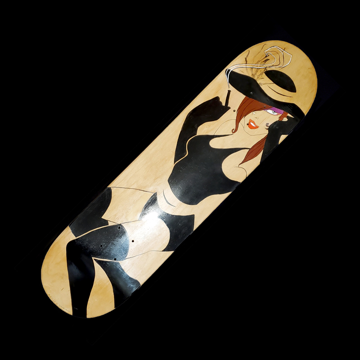A skateboard deck with a woman wearing black thigh highs, a hat, black gloves, and a black bathing suit. She has brown hair and green eyes