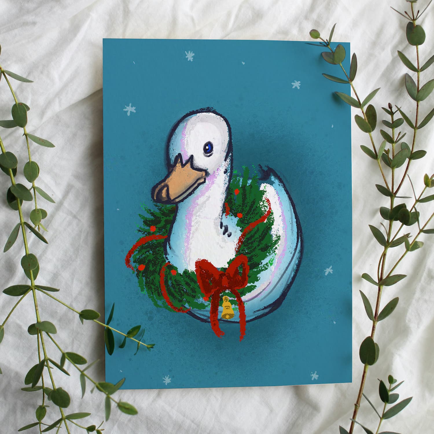 A mockup of a holiday greeting card of an illustration of a duck with a wreath around its neck.